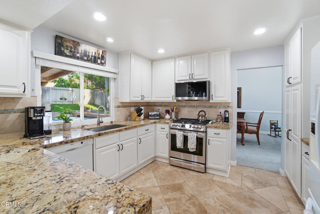 1288 Old Ranch Road Camarillo, CA 93012 - Photo 11 of 61 a kitchen with stainless steel appliances granite countertop a stove top oven a sink a dining table and chairs with wooden floor