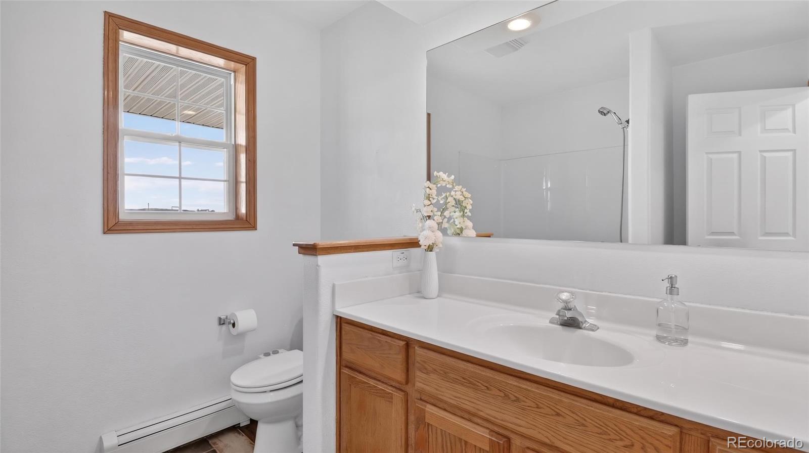 44166 East Iliff Trail Bennett, CO 80102 - Photo 20 of 50 a bathroom with a granite countertop sink mirror vanity and toilet