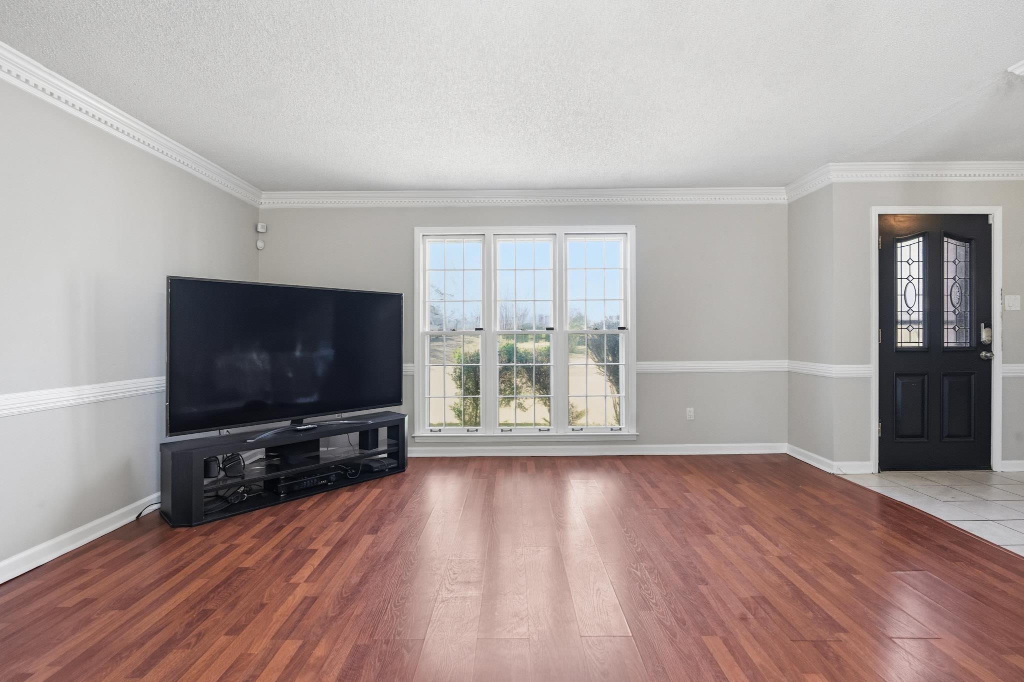 7105 Cutter Mill Road Memphis, TN 38141 - Photo 13 of 23 Unfurnished living room featuring hardwood / wood-style floors, a textured ceiling, and crown molding