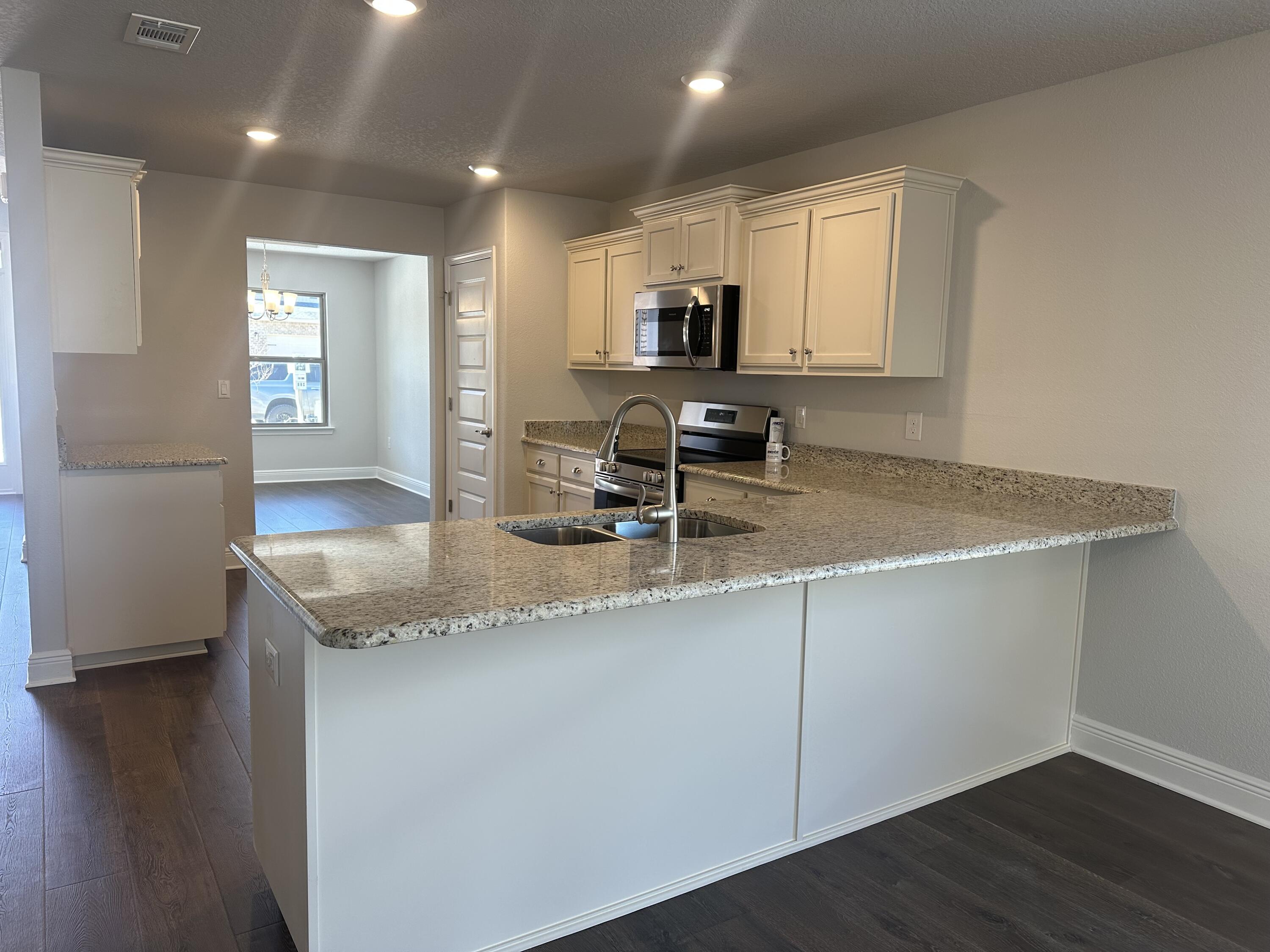 329 Keswick Lane Crestview, FL 32536 - Photo 7 of 22 a kitchen with granite countertop a sink a stove cabinets and wooden floor