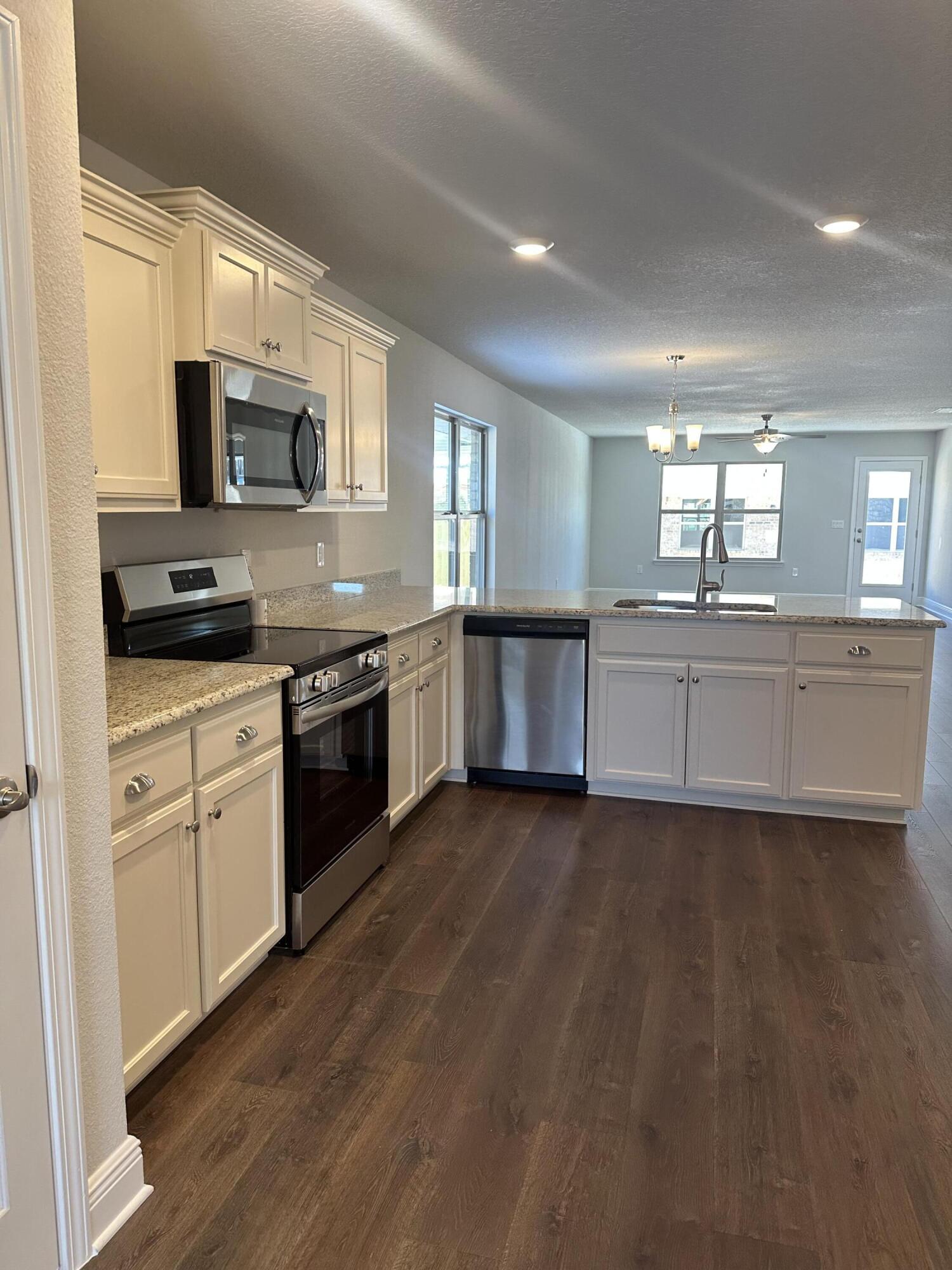 329 Keswick Lane Crestview, FL 32536 - Photo 8 of 22 a large kitchen with stainless steel appliances granite countertop a stove top oven a sink dishwasher and a microwave oven with cabinets