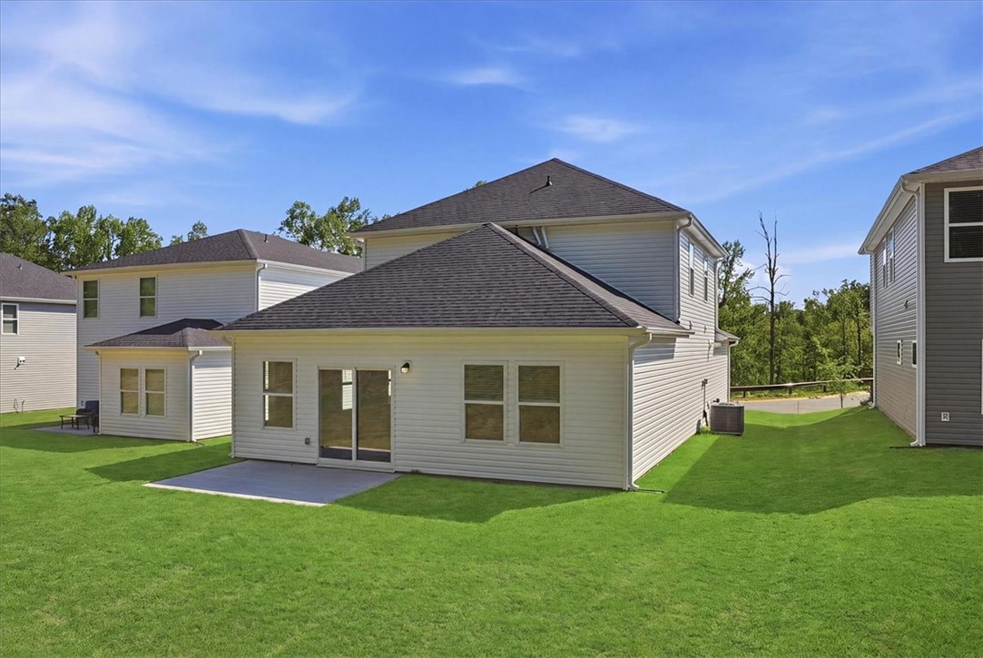 973 Penfold Pointe Point Blythewood, SC 29016 - Photo 29 of 39 A well-maintained lawn stretches behind a residence featuring a concrete patio and a serene treed backdrop.