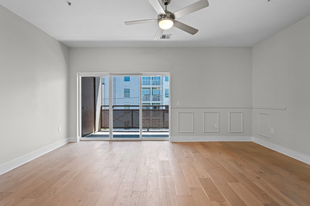 2827 Manor Road, Unit 2201 Austin, TX 78722 - Photo 26 of 40 Spacious interior with wood-finish flooring, a contemporary ceiling fan with integrated lighting, and a sliding glass door opening to a private balcony