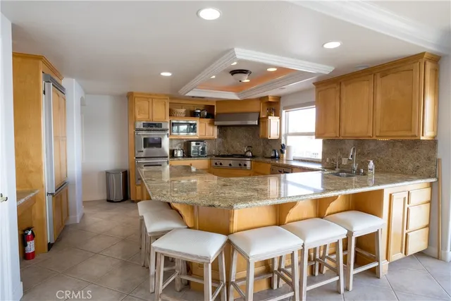 a kitchen with stainless steel appliances granite countertop a table chairs sink and cabinets