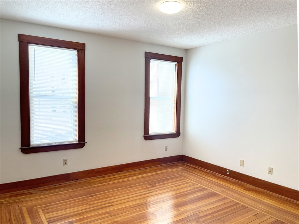 25 Bennett Street, Unit 2 Beverly, MA 01915 - Photo 4 of 17 an empty room with wooden floor and windows