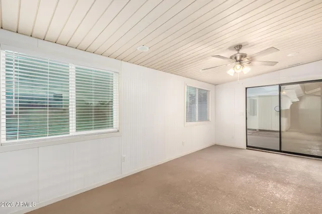 an empty room with chandelier fan and windows