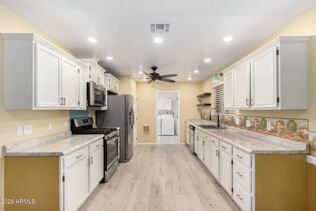 a large kitchen with stainless steel appliances granite countertop a lot of counter space and wooden floors