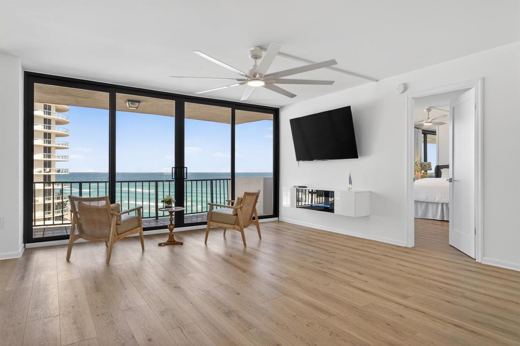 a living room with furniture floor to ceiling window wooden floor and a flat screen tv