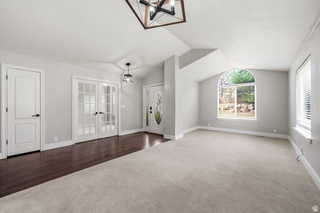Spacious interior featuring a vaulted ceiling and a mix of light carpeting and dark wood-finish flooring