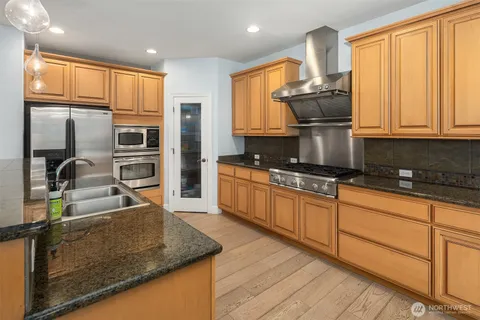 a kitchen with kitchen island granite countertop a sink stainless steel appliances and cabinets