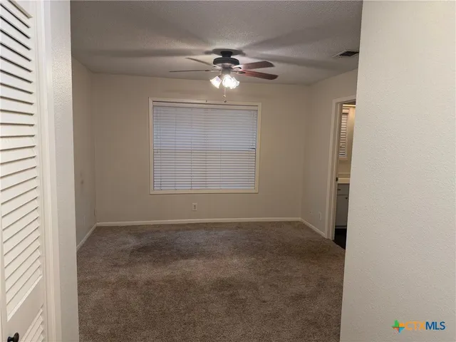 an empty room with a chandelier fan and windows