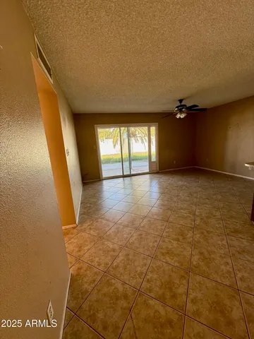 a view of an empty room with a ceiling fan and window