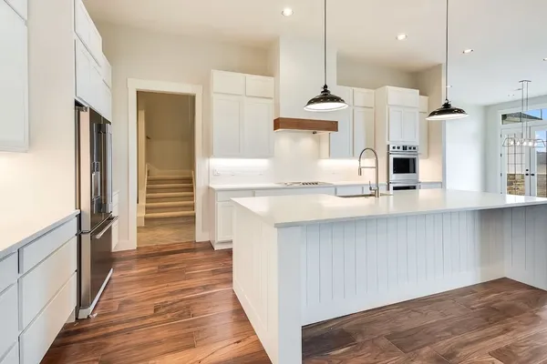 a kitchen with stainless steel appliances a refrigerator and a wooden floor
