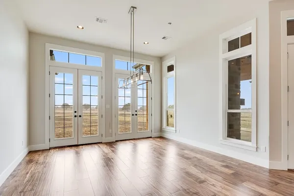 a view of an empty room with window and wooden floor