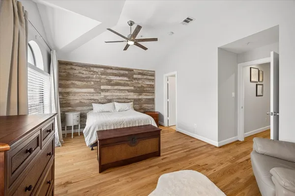 a spacious bedroom with a bed and wooden floor