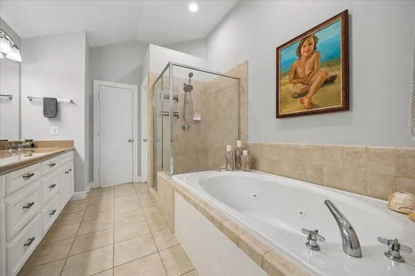 a bathroom with a tub a sink and glass door shower
