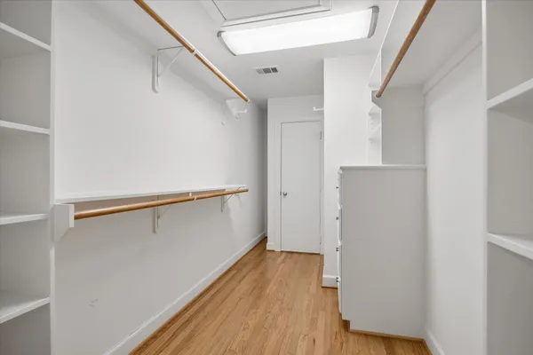 a view of walk in closet with wooden floor