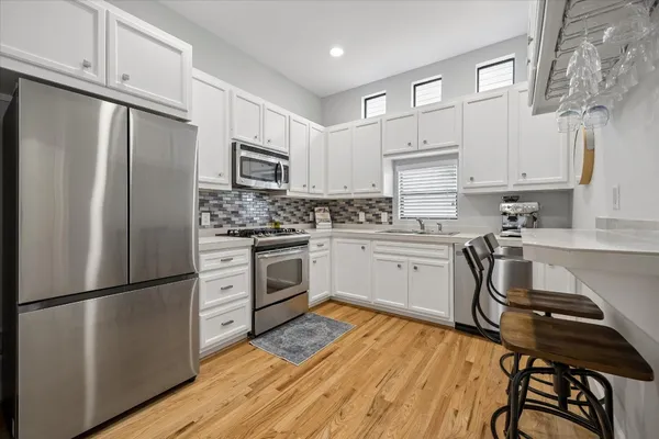a kitchen with white cabinets stainless steel appliances and a refrigerator