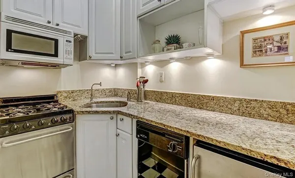 a kitchen with granite countertop a sink stainless steel appliances and cabinets
