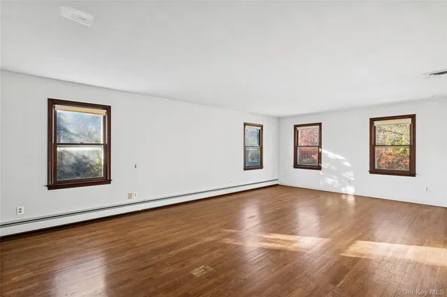 a view of an empty room with wooden floor and window
