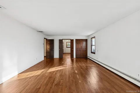 a view of an empty room with wooden floor and window