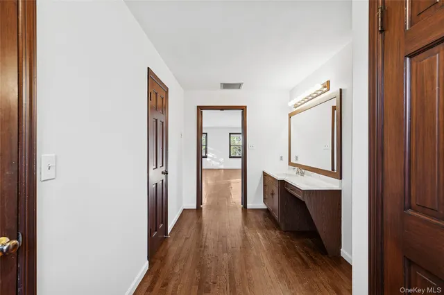 a hallway with white cabinets and wooden floor