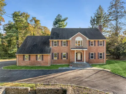 a view of a brick house next to a yard with big trees