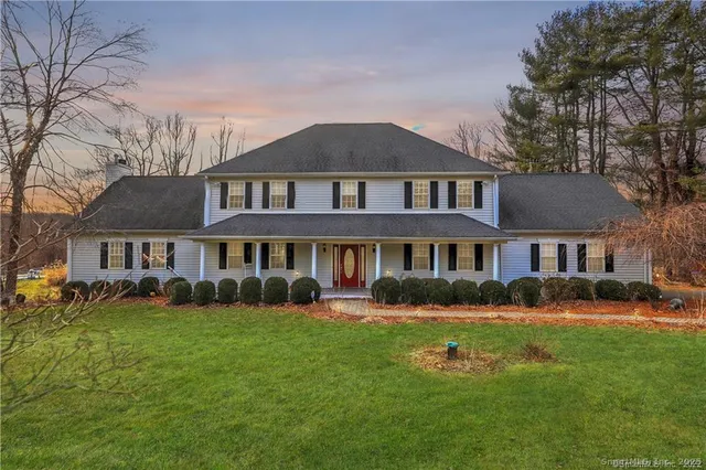 a front view of a house with a garden and trees