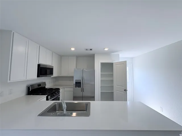 a kitchen with a refrigerator and a stove top oven