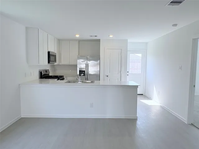 a view of kitchen with stainless steel appliances granite countertop a stove a sink and a refrigerator