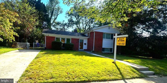 a view of house with outdoor seating area and large tree