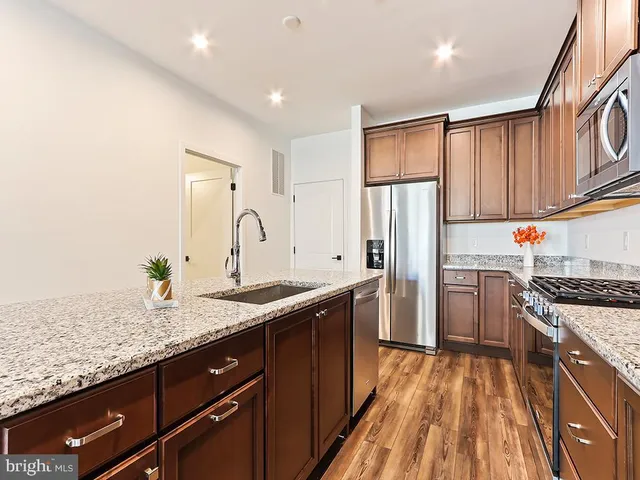 a kitchen with stainless steel appliances granite countertop a sink stove and refrigerator