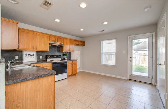 a kitchen with stainless steel appliances granite countertop a stove a sink and a refrigerator