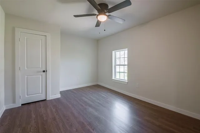 an empty room with wooden floor chandelier fan and windows