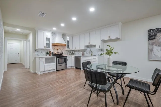 a kitchen with stainless steel appliances granite countertop a table chairs refrigerator sink and cabinets