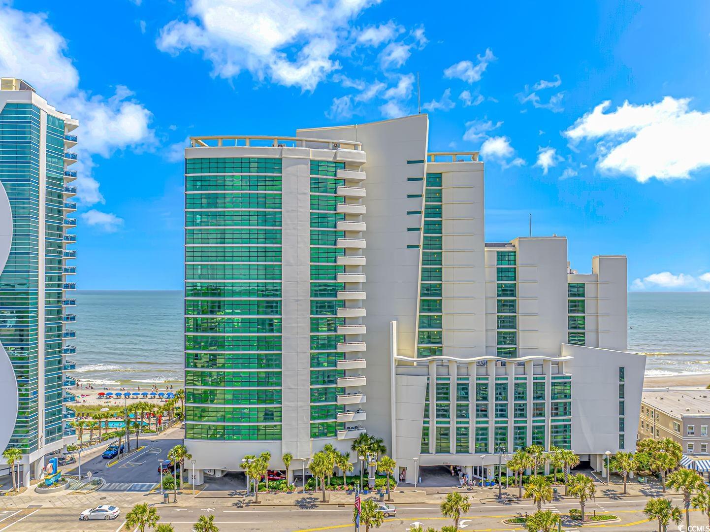 View of apartment building / complex featuring view of water and beach