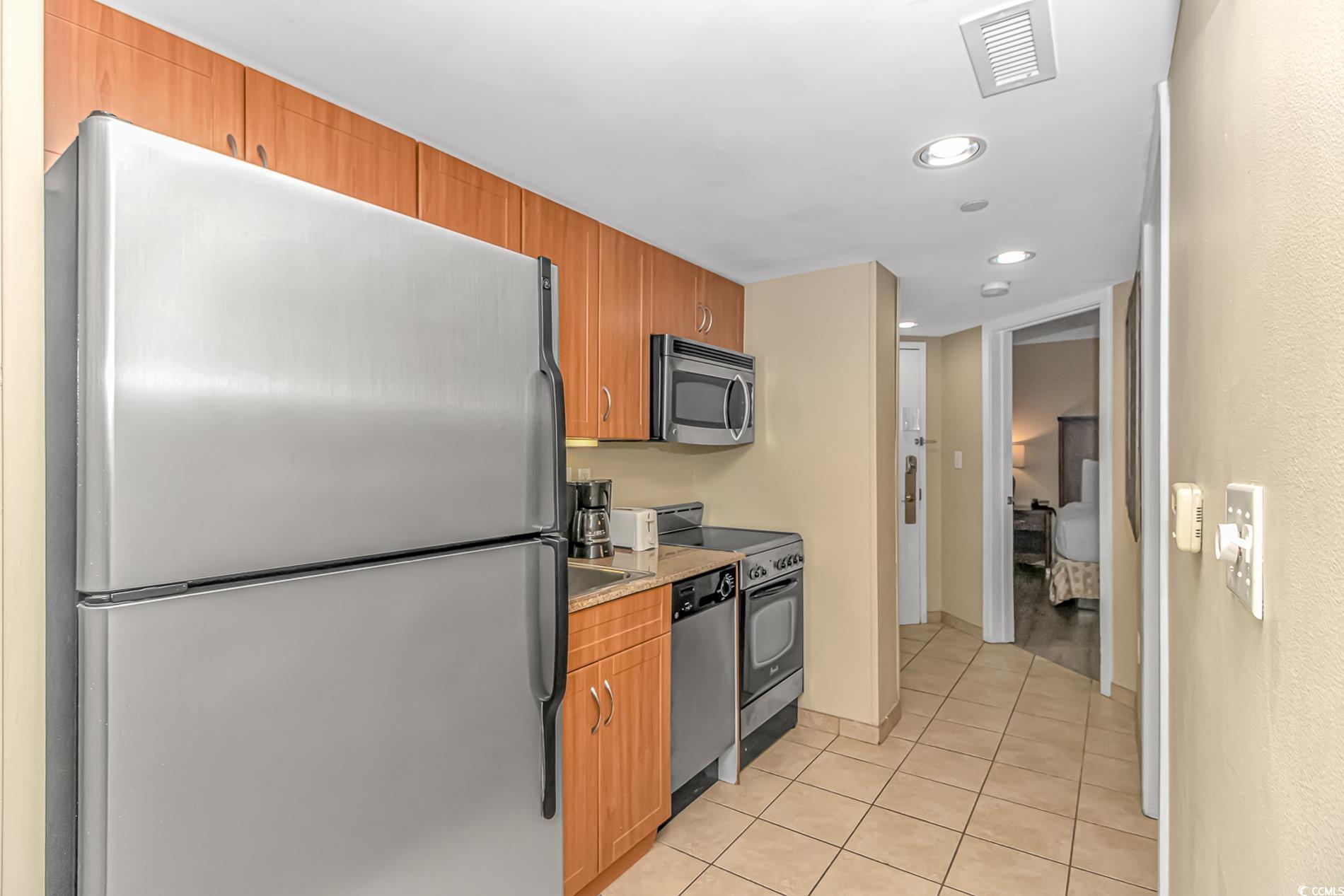 201 South Ocean Boulevard, Unit 1905 Myrtle Beach, SC 29577 - Photo 14 of 32 Kitchen featuring stainless steel appliances, light tile patterned floors, recessed lighting, brown cabinets, and light stone counters