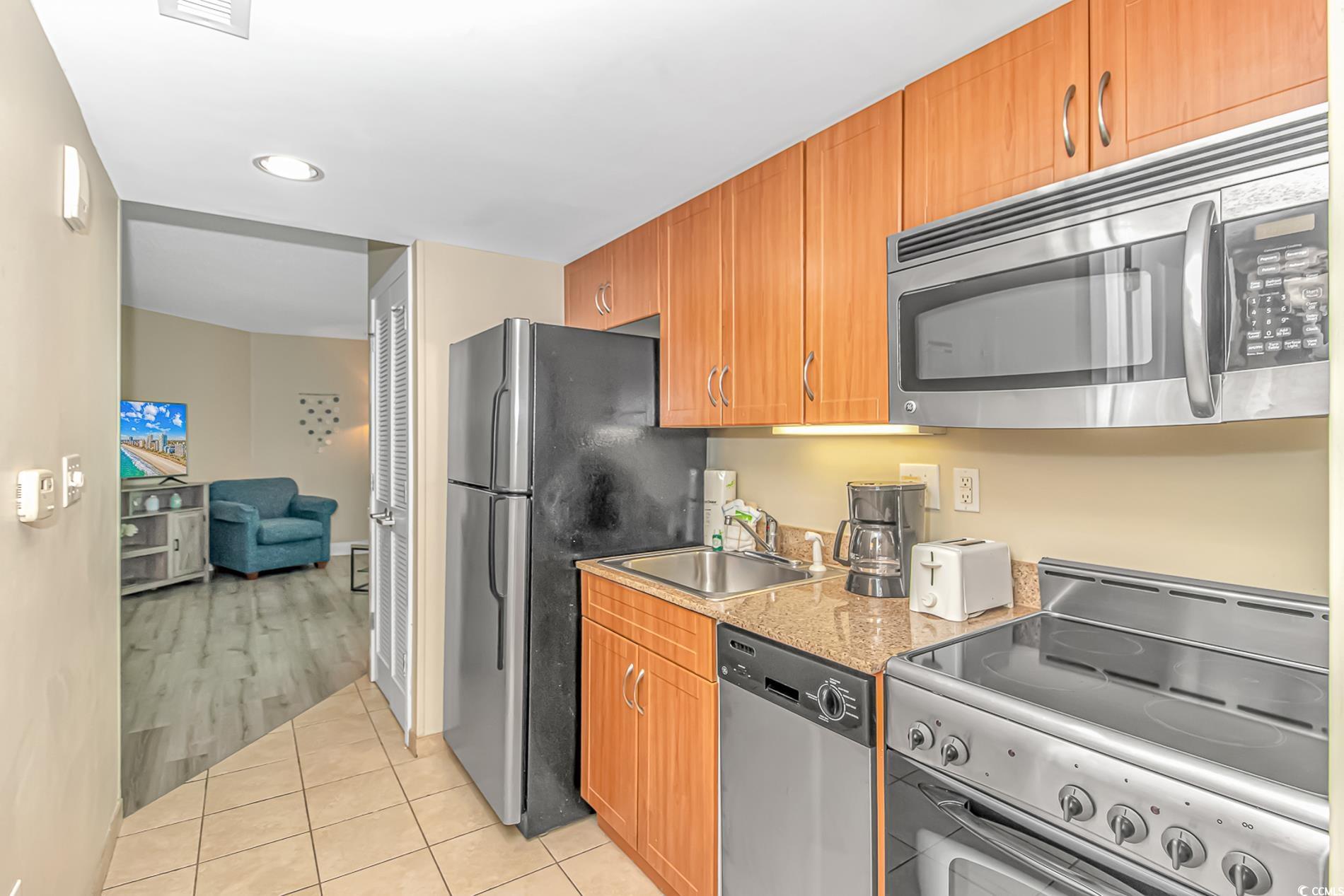 201 South Ocean Boulevard, Unit 1905 Myrtle Beach, SC 29577 - Photo 15 of 32 Kitchen featuring stainless steel appliances, light tile patterned floors, brown cabinetry, recessed lighting, and light stone counters