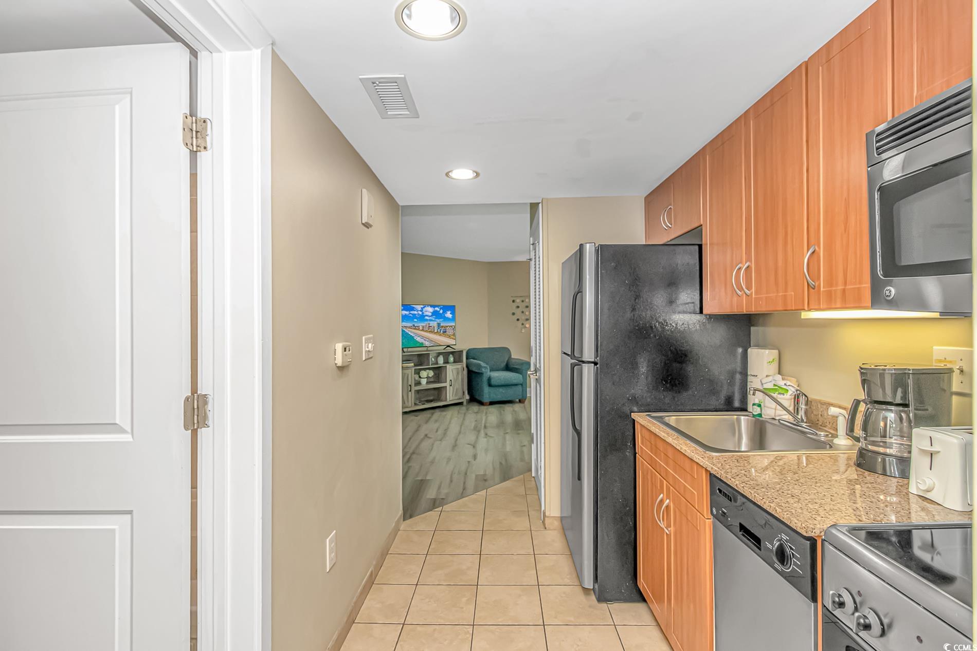 201 South Ocean Boulevard, Unit 1905 Myrtle Beach, SC 29577 - Photo 16 of 32 Kitchen featuring light tile patterned floors, stainless steel appliances, brown cabinetry, recessed lighting, and light stone counters