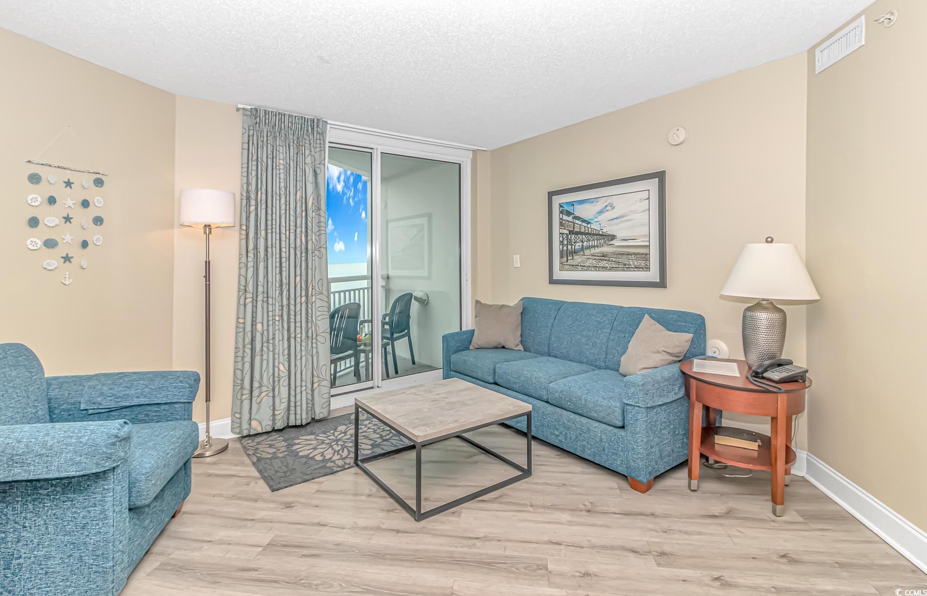 201 South Ocean Boulevard, Unit 1905 Myrtle Beach, SC 29577 - Photo 5 of 32 Living area with light wood-style flooring, floor to ceiling windows, and a textured ceiling