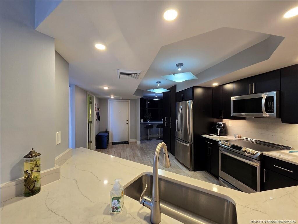 9500 South Ocean Drive, Unit 1908 Jensen Beach, FL 34957 - Photo 9 of 25 a kitchen with stainless steel appliances kitchen island granite countertop a sink refrigerator and cabinets