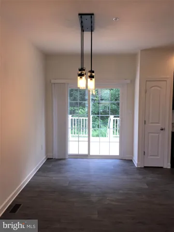 a view of a room with wooden floor chandeliers and kitchen view