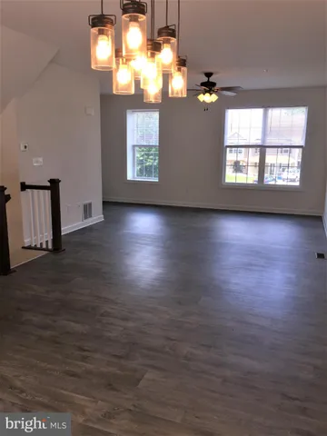 an empty room with wooden floor chandelier and windows