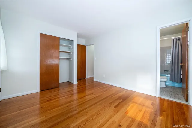 a view of an empty room with wooden floor and closet