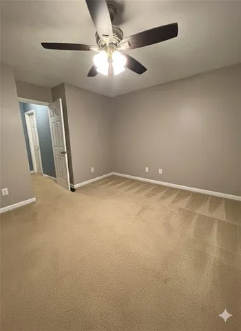 an empty room with a chandelier fan and windows