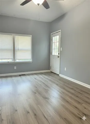 an empty room with wooden floor and windows