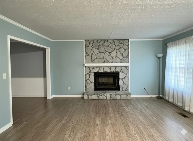 a view of an empty room with wooden floor fireplace and a window