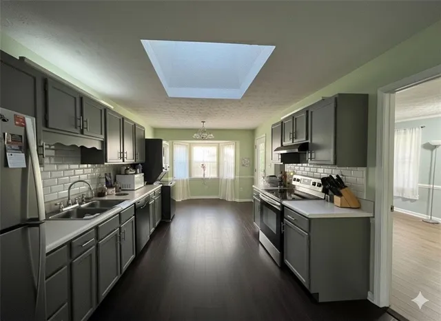 a kitchen with stainless steel appliances a stove top oven a sink dishwasher a refrigerator and cabinets with wooden floor