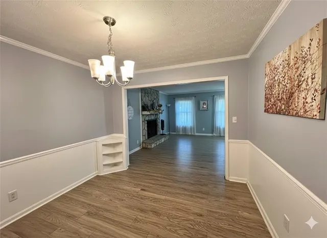 a view of a hallway with wooden floor and chandelier