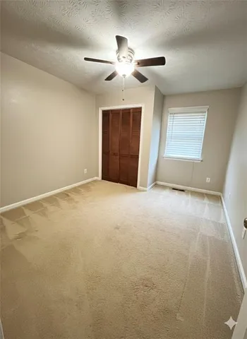 an empty room with chandelier fan and windows